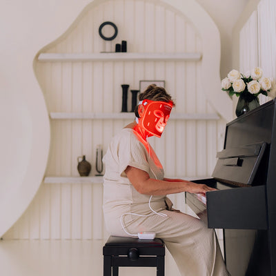 Vrouw speelt piano met het Liroma LED masker voor het gezicht